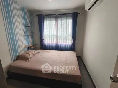 Cozy bedroom with modern decor and large window offering natural light.