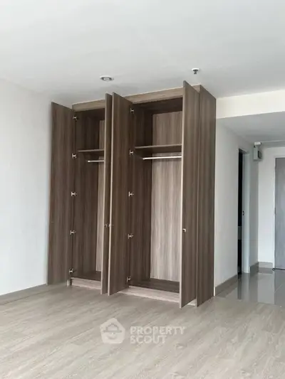 Spacious empty room with modern wooden closets and sleek flooring