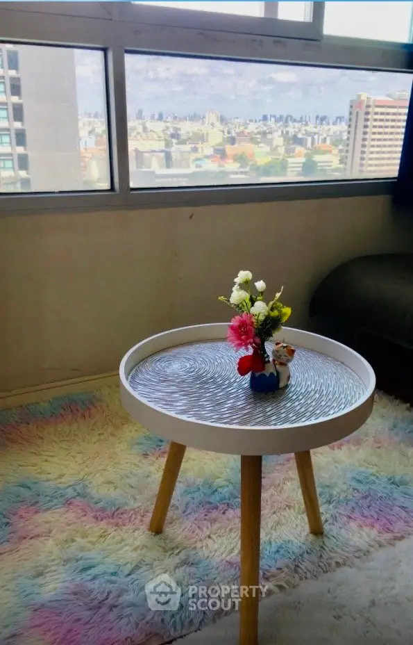 Charming living room with colorful rug and city view, perfect for relaxation and enjoying urban scenery.