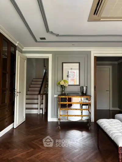 Elegant living room with wooden flooring, stylish furniture, and staircase in a modern home.