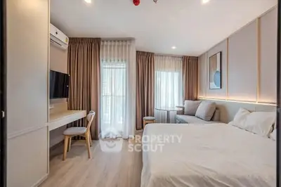 Modern bedroom with stylish decor, large windows, and cozy seating area.