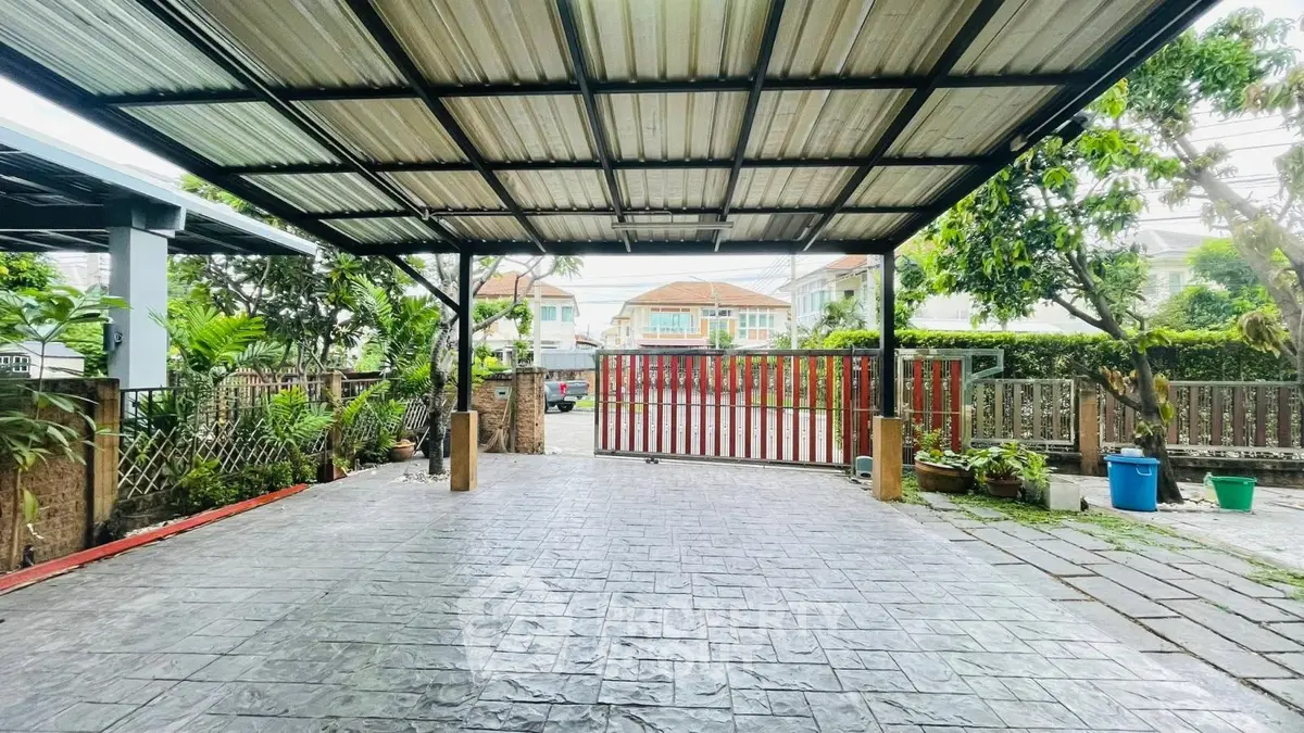 Spacious covered parking area with gated entrance and lush greenery