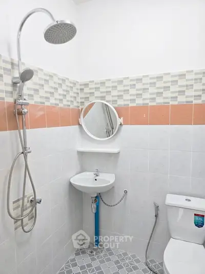 Modern bathroom with shower, sink, and toilet in a tiled setting.