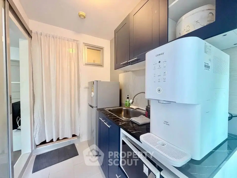 Modern kitchen with sleek cabinetry and compact appliances in a cozy apartment setting.