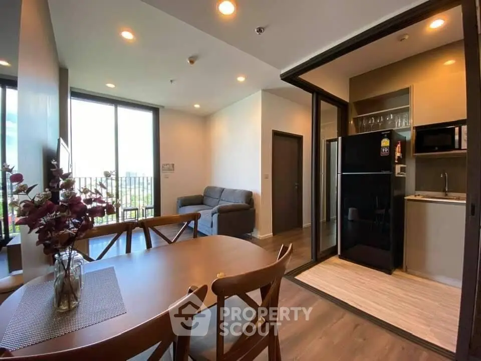 Modern open-plan living room with dining area and compact kitchen in a stylish apartment.