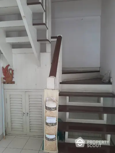 Charming white wooden staircase with under-stair storage in a bright, airy home, perfect for maximizing space in style.