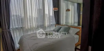 Cozy bedroom with large windows and elegant curtains in a modern apartment.