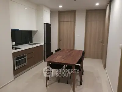 Modern kitchen with sleek cabinetry and dining area in contemporary apartment