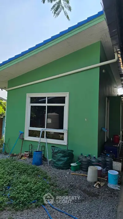Charming green exterior of a single-story home with blue roof and garden area.