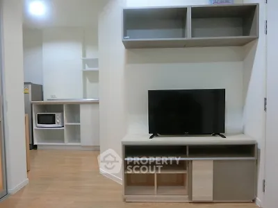 Modern living room with TV stand and open kitchen layout in cozy apartment.