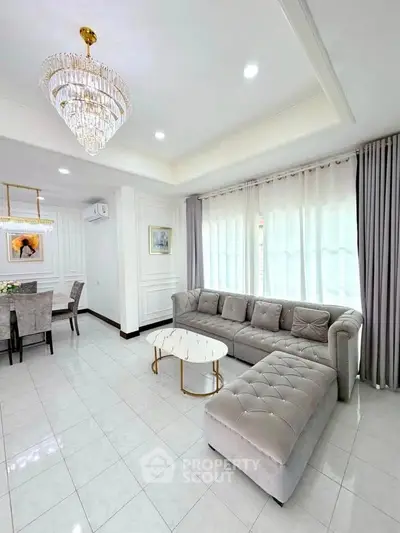 Luxurious living room with elegant chandelier and plush sectional sofa in a modern open layout.