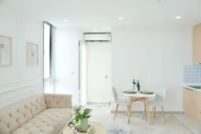 Bright and modern living room with cozy sofa and dining area in open layout apartment.