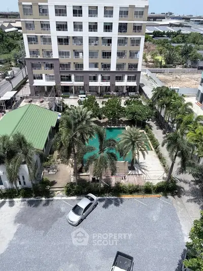 Modern apartment building with pool and lush greenery in urban setting.