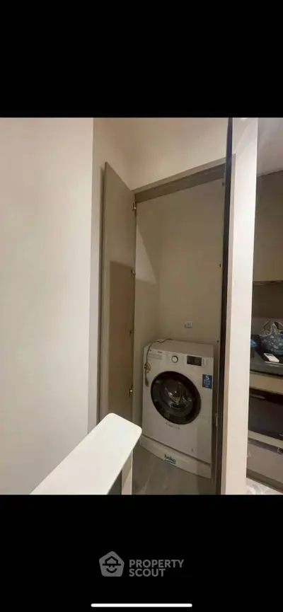 Compact laundry area with modern washing machine in a cozy apartment.