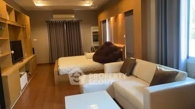 Spacious studio with modern decor and cozy ambiance, featuring a comfortable bed and stylish seating area.