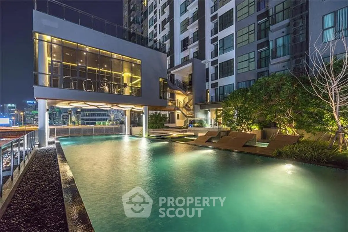 Luxurious condominium with illuminated pool and modern architecture at night.