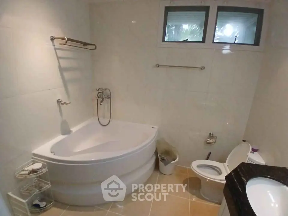 Spacious bathroom with corner bathtub and modern fixtures.