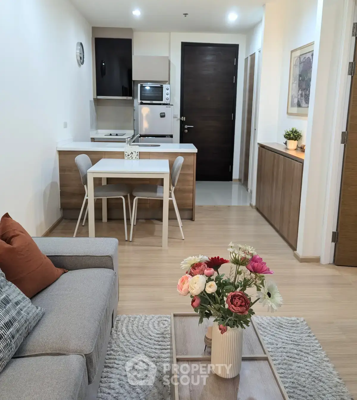 Modern open-layout living room with cozy seating and stylish kitchen area.