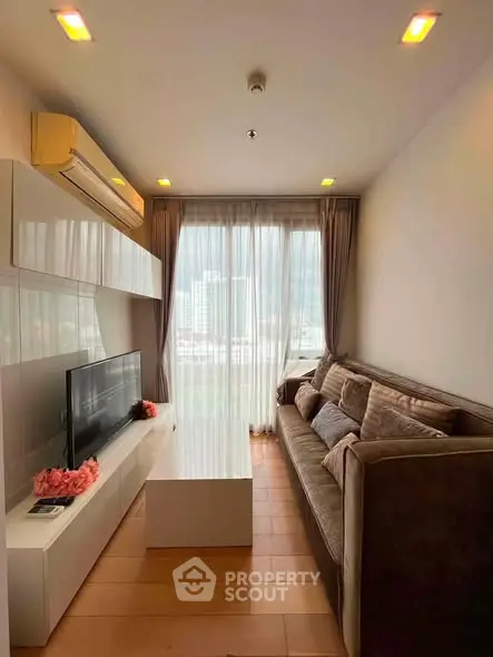 Modern living room with large window and city view, featuring sleek furniture and cozy ambiance.