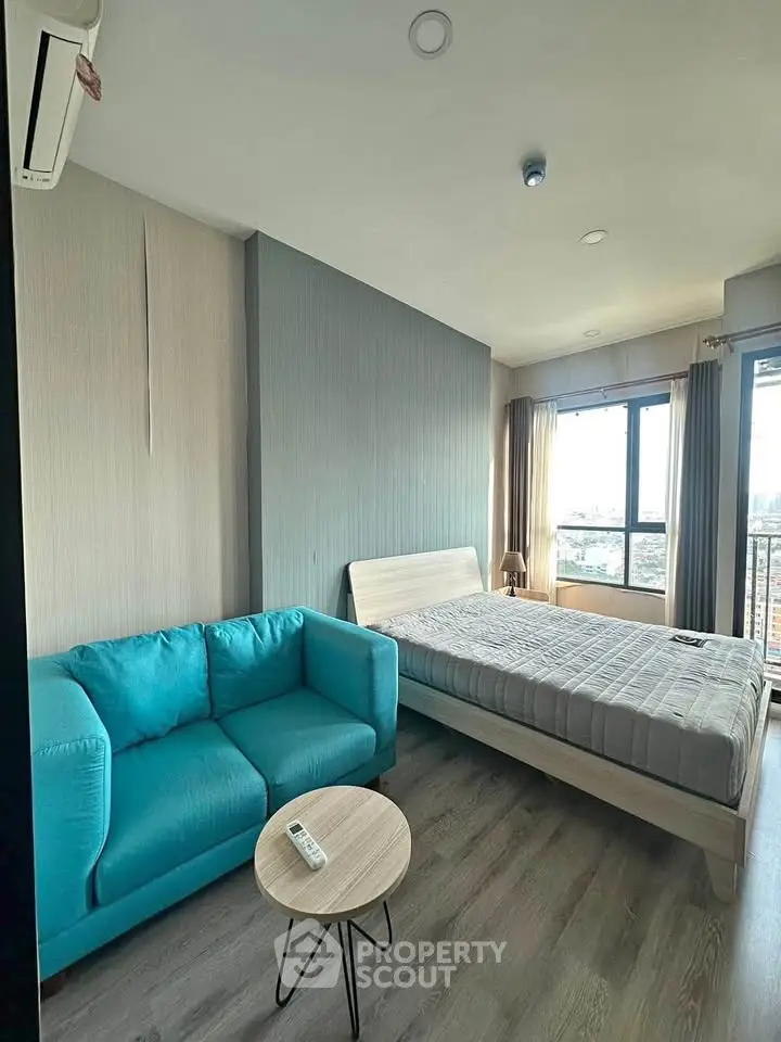 Modern bedroom with blue sofa and large window offering city views