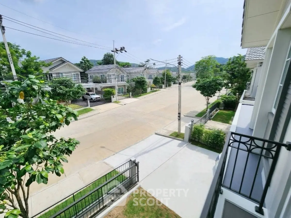 Charming suburban street view from a modern balcony, showcasing serene neighborhood and lush greenery.