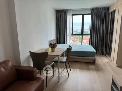 Modern studio apartment with large window and city view, featuring cozy dining area and comfortable bed.