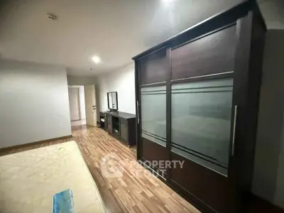 Spacious bedroom with wooden flooring and modern wardrobe
