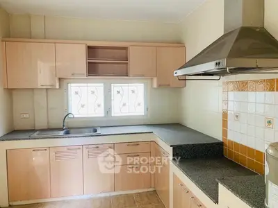Spacious kitchen with modern cabinetry and stainless steel range hood