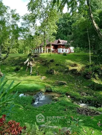 Charming countryside home surrounded by lush greenery and a serene stream, perfect for nature lovers.