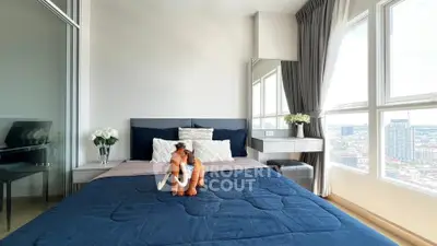 Modern bedroom with city view, featuring stylish decor and large windows for natural light.