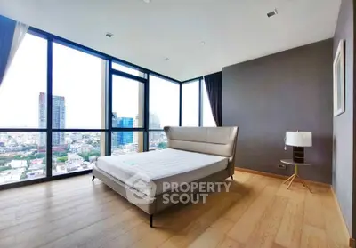 Spacious bedroom with floor-to-ceiling windows offering stunning city views in a modern high-rise apartment.