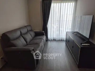 Modern living room with sleek sofa and large TV, featuring floor-to-ceiling window with elegant curtains.