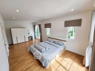 Spacious bedroom with wooden flooring and large windows offering natural light