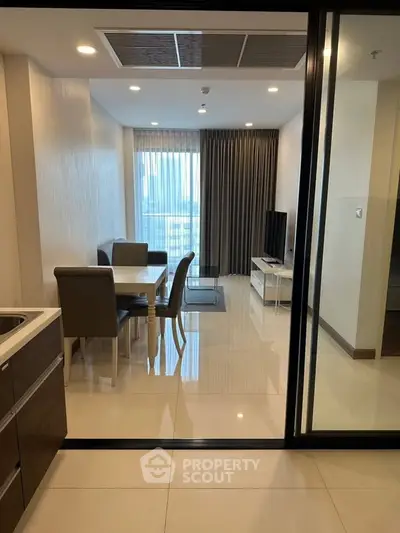 Modern living room with dining area and city view, featuring sleek furniture and large windows.