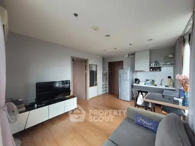 Modern living room with open kitchen, wooden flooring, and cozy seating area.