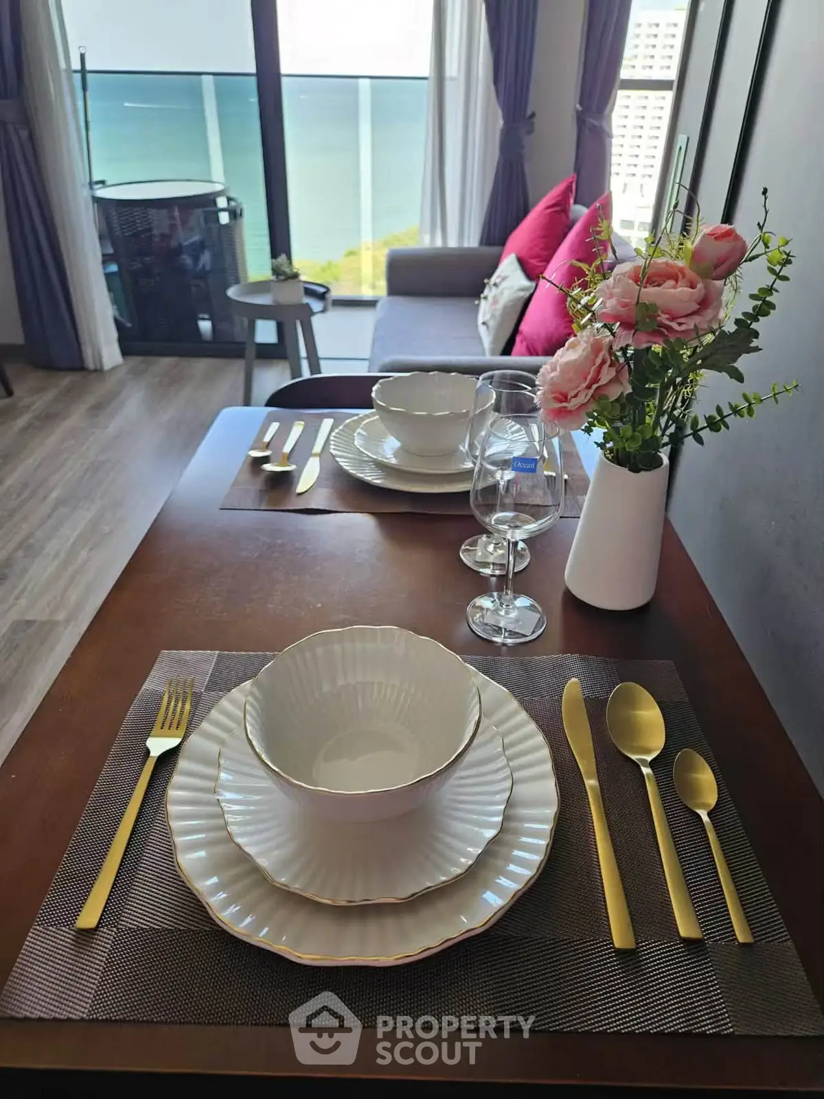 Elegant dining setup with ocean view from modern apartment balcony
