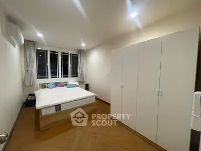 Spacious bedroom with modern wardrobe and large window for natural light.