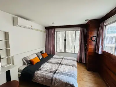 Spacious bedroom with modern decor and large windows offering natural light.