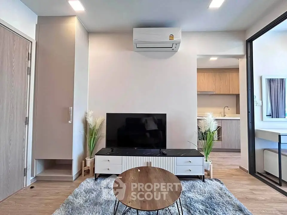 Modern living room with sleek furniture and open kitchen layout, featuring air conditioning and stylish decor.