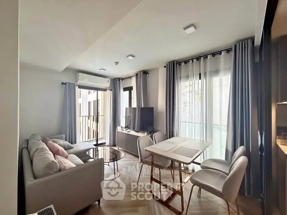 Modern living room with stylish furniture and natural light, featuring a cozy sofa and dining area.