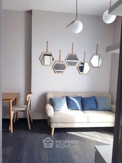 Stylish living room with modern decor and geometric mirrors, featuring a cozy sofa and elegant lighting.