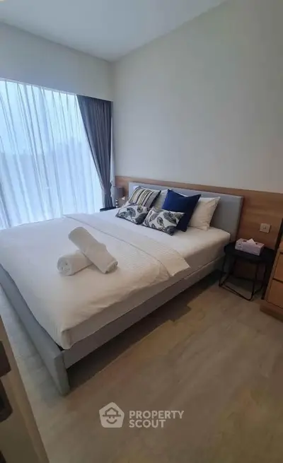 Modern bedroom with large window and stylish decor in a cozy apartment.