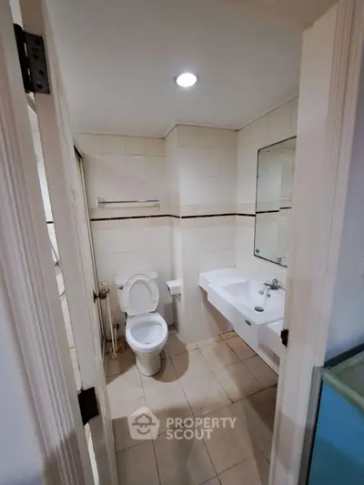 Modern bathroom with sleek fixtures and tiled walls, featuring a toilet and sink.