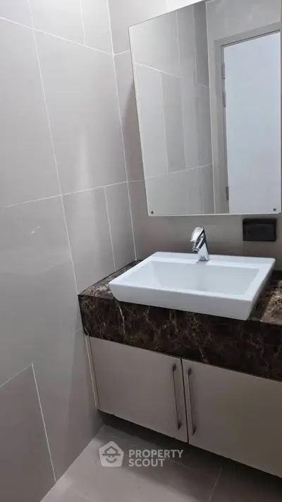 Modern bathroom with sleek sink and marble countertop in contemporary apartment.