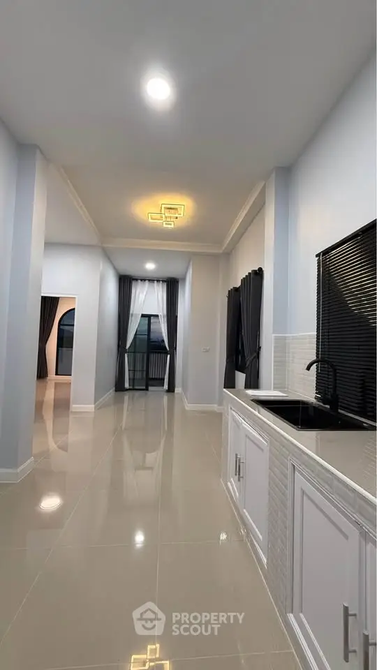 Spacious modern kitchen with sleek design and open layout, featuring elegant lighting and glossy tiled floors.