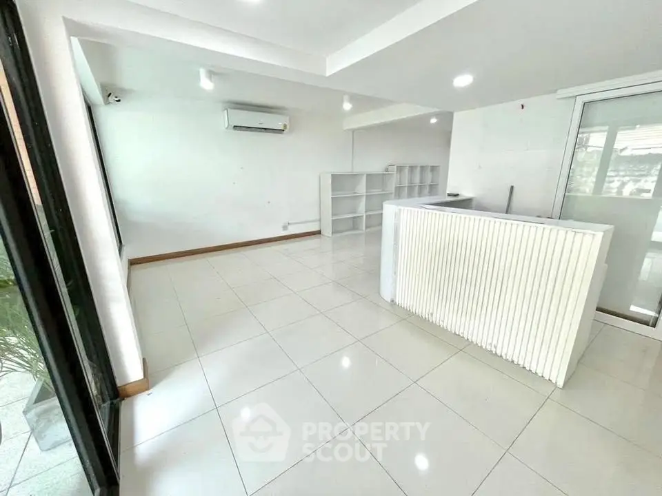 Spacious modern living room with sleek white tiles and ample natural light, perfect for contemporary living.