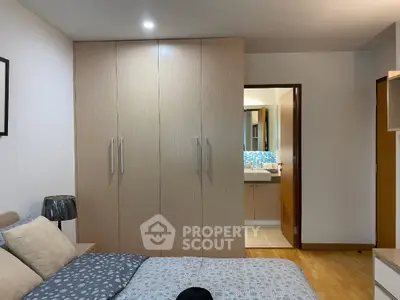 Modern bedroom with built-in wardrobe and view into stylish bathroom