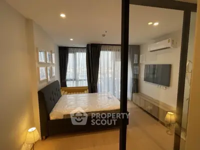 Modern bedroom with large windows and city view, featuring a stylish bed and wall-mounted TV.