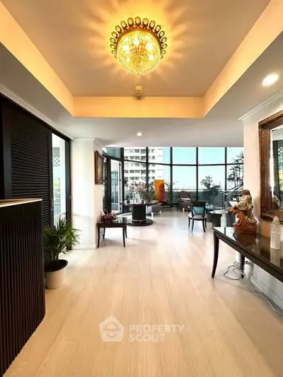 Luxurious living room with elegant chandelier and floor-to-ceiling windows offering stunning city views.