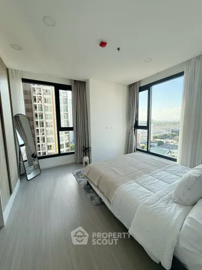 Modern bedroom with large windows offering stunning city views in a high-rise apartment.